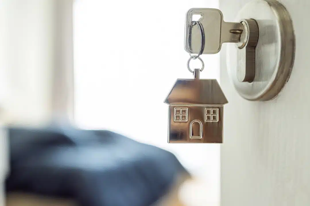 House-shaped keychain hanging from a door lock symbolizing tenant access rights and California lock change laws.