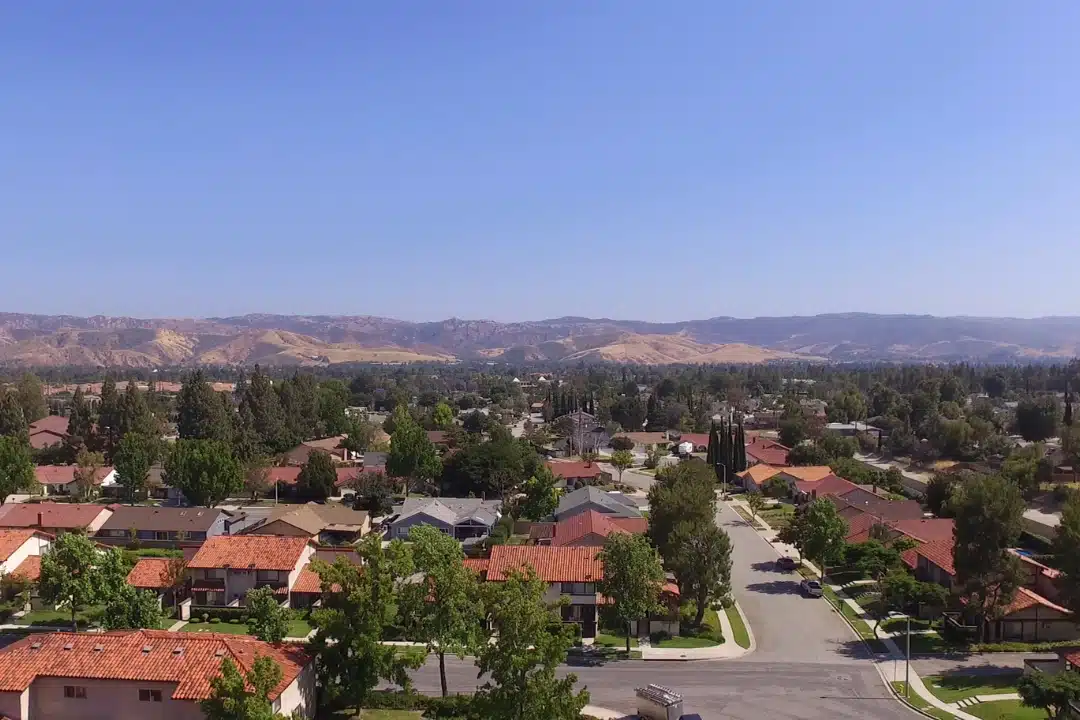Aerial view of Simi Valley, California showing residential neighborhoods, rolling hills, and surrounding mountains under clear blue skies.