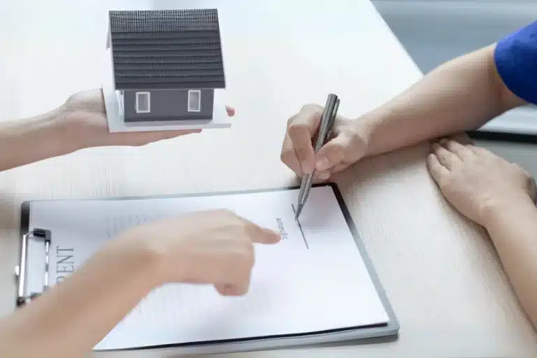 Tenant signing rental agreement while landlord holds house model, illustrating premises liability, bad-faith repairs, and treble damages in California tenant harassment and personal injury cases.